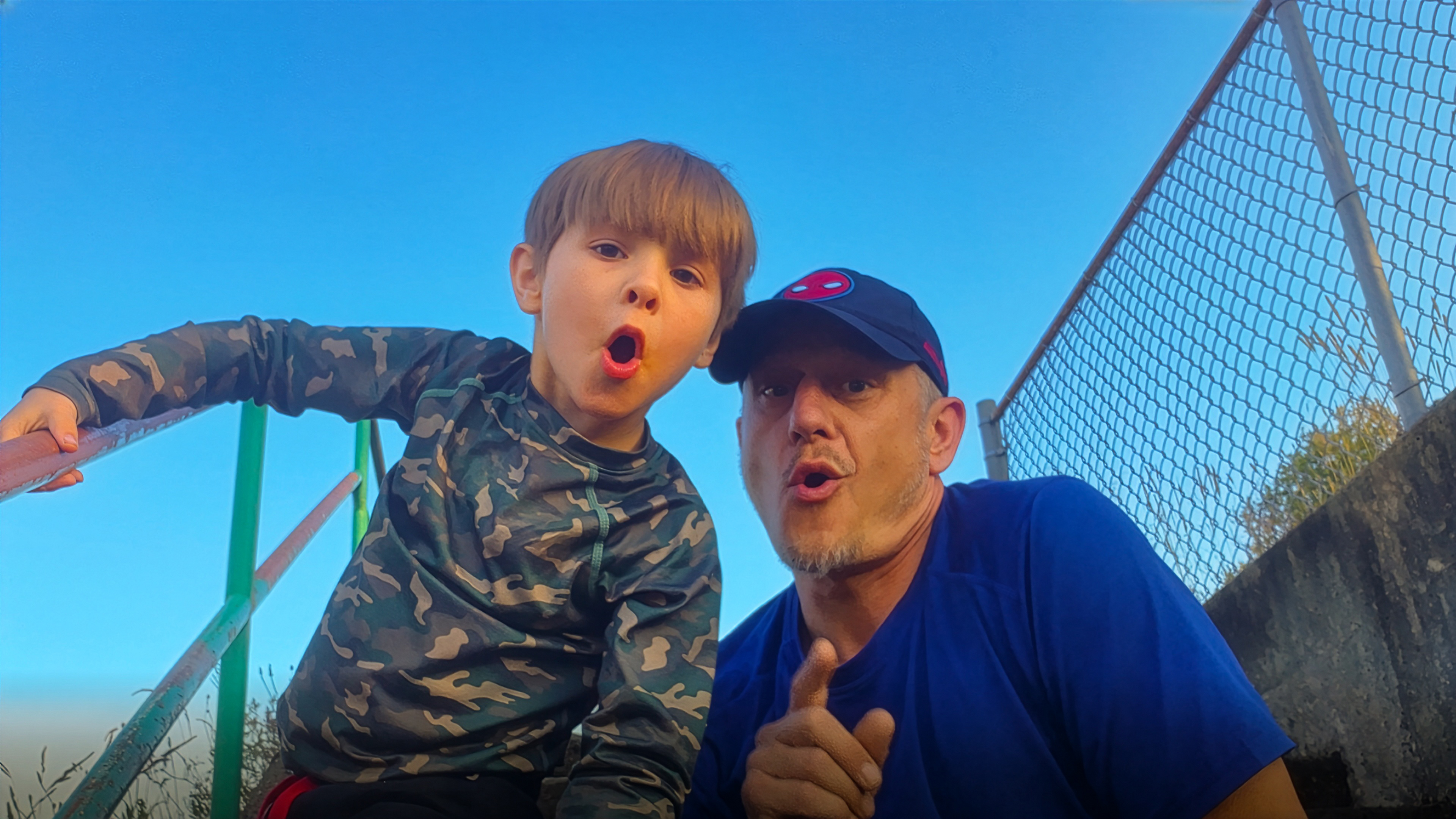 Father and son making silly faces at playground