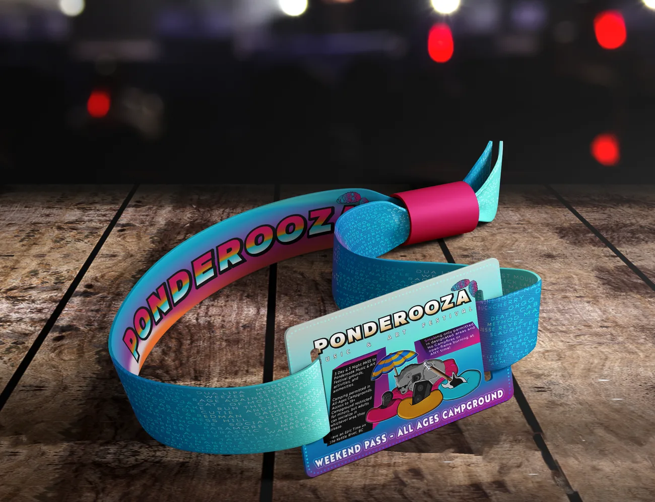Teal fabric wristband pass and a printed all-ages camping pass card on a wooden surface