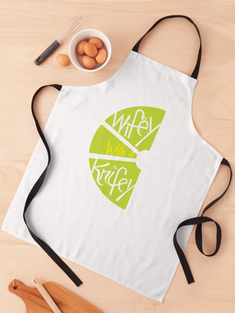 White apron carrying the lime logo, photographed from above with eggs and a rolling pin